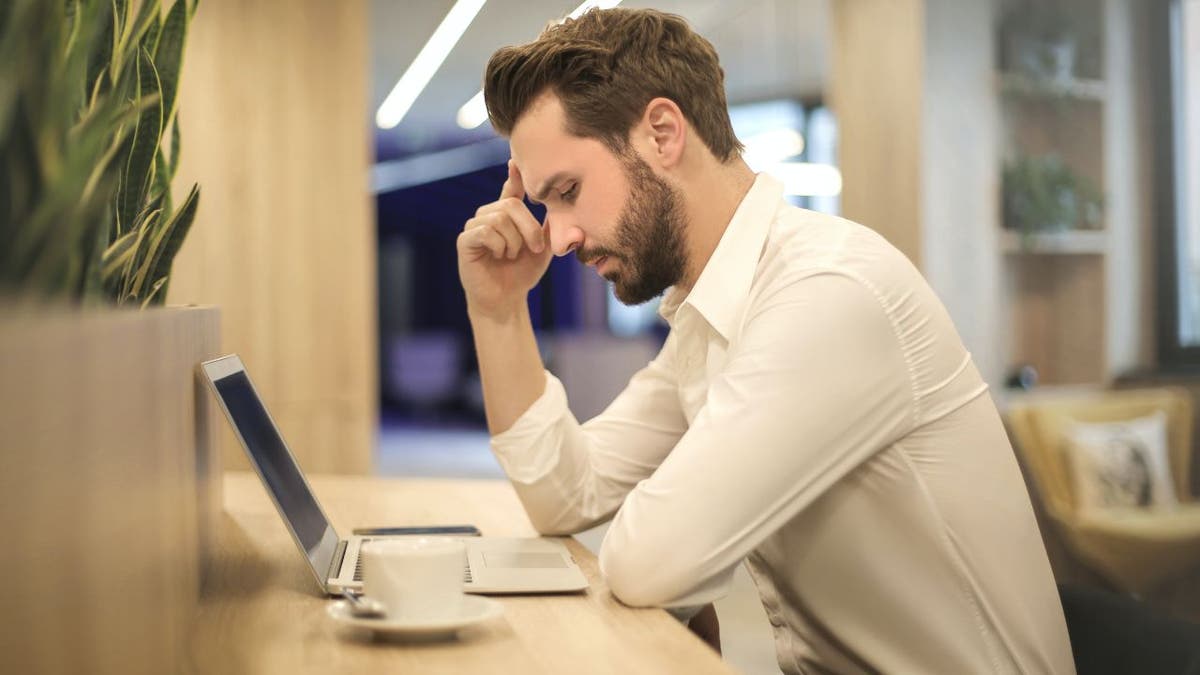 Concerned man looks at laptop