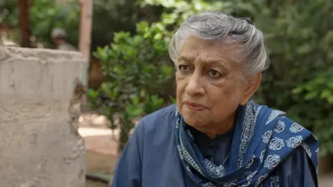 A woman looks at a point to the left of the camera