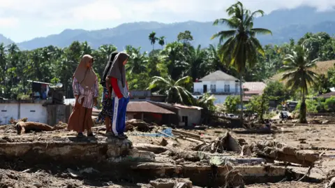 Reuters Local residents inspect an area hit by deadly flash floods following heavy rains in Palembayan, Agam regency, West Sumatra province, Indonesia, December 1, 2025