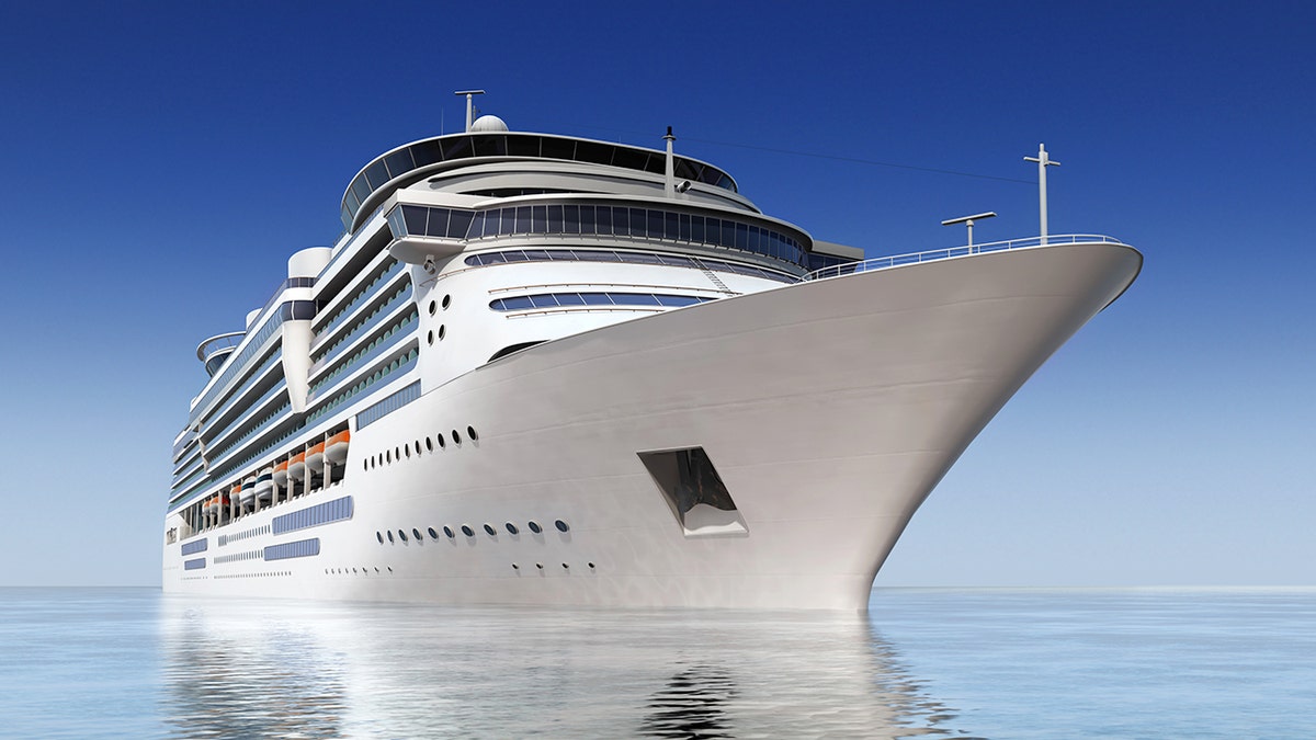 Luxury white cruise ship shot at angle at water level on a clear day.